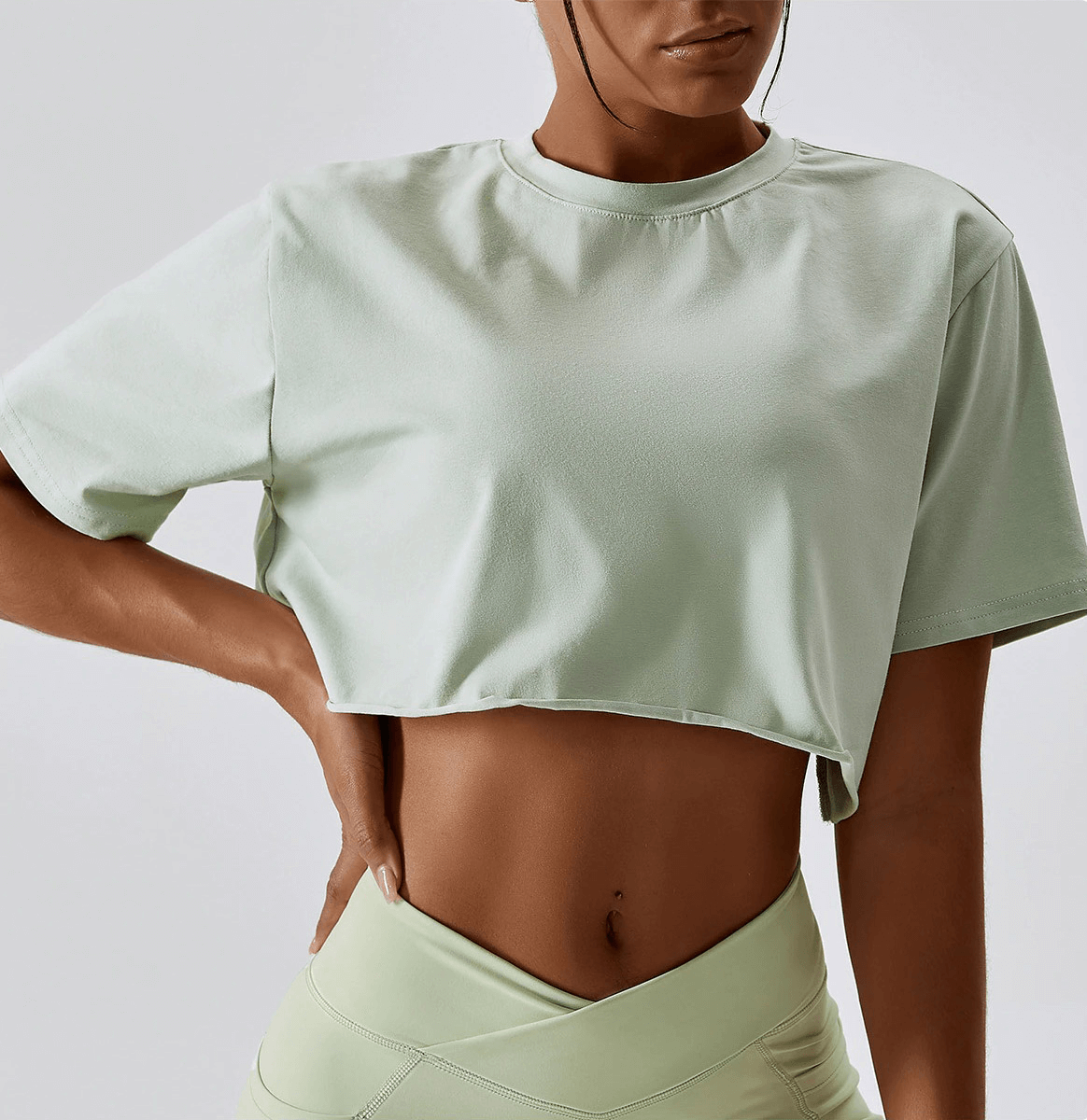 Woman wearing a sports loose crop top for training and running, O-neck, short sleeve, perfect for yoga, running, and workouts.